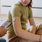 Diabetic girl with a CGM sensor on her arm.